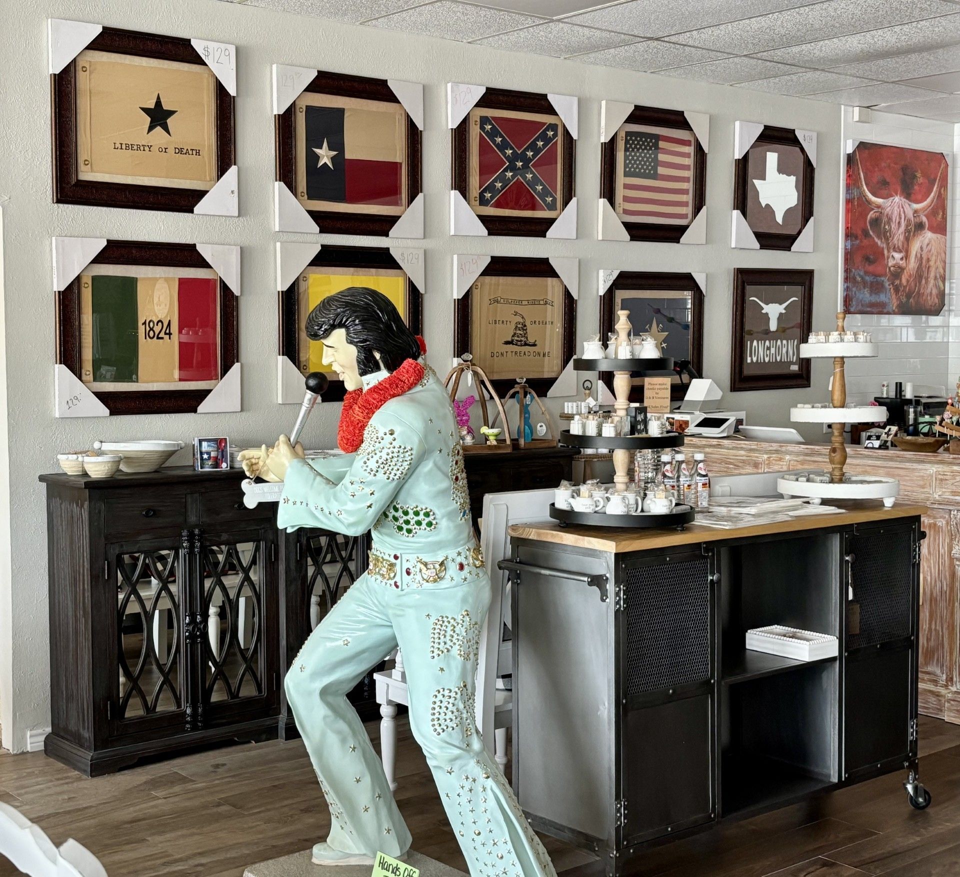 A statue of Elvis Presley in a room with flags on the wall.