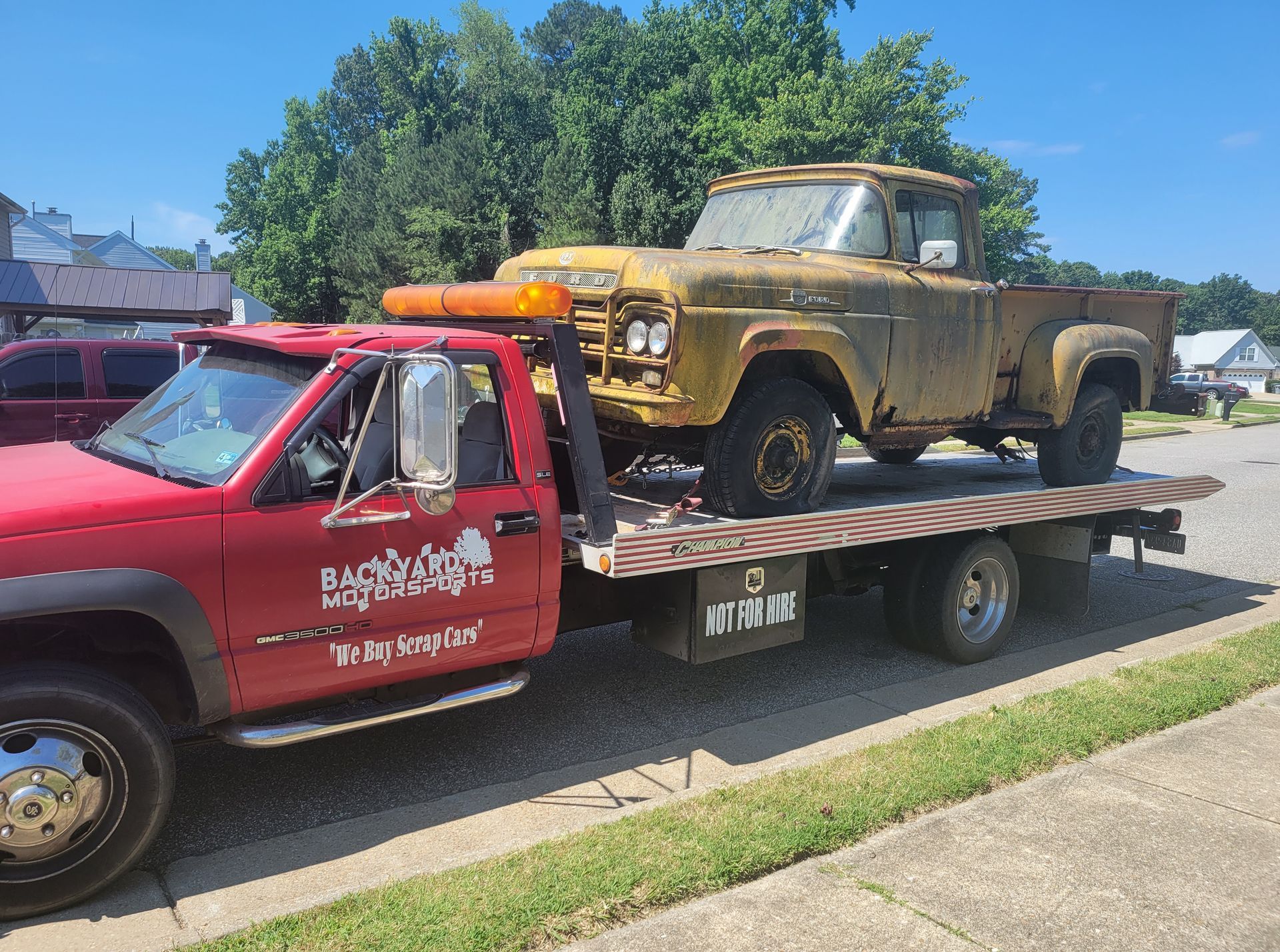 A yellow truck is being towed by a red tow truck.