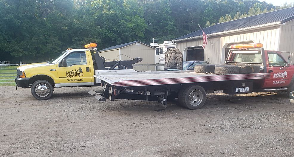 Two tow trucks are parked next to each other in front of a building.