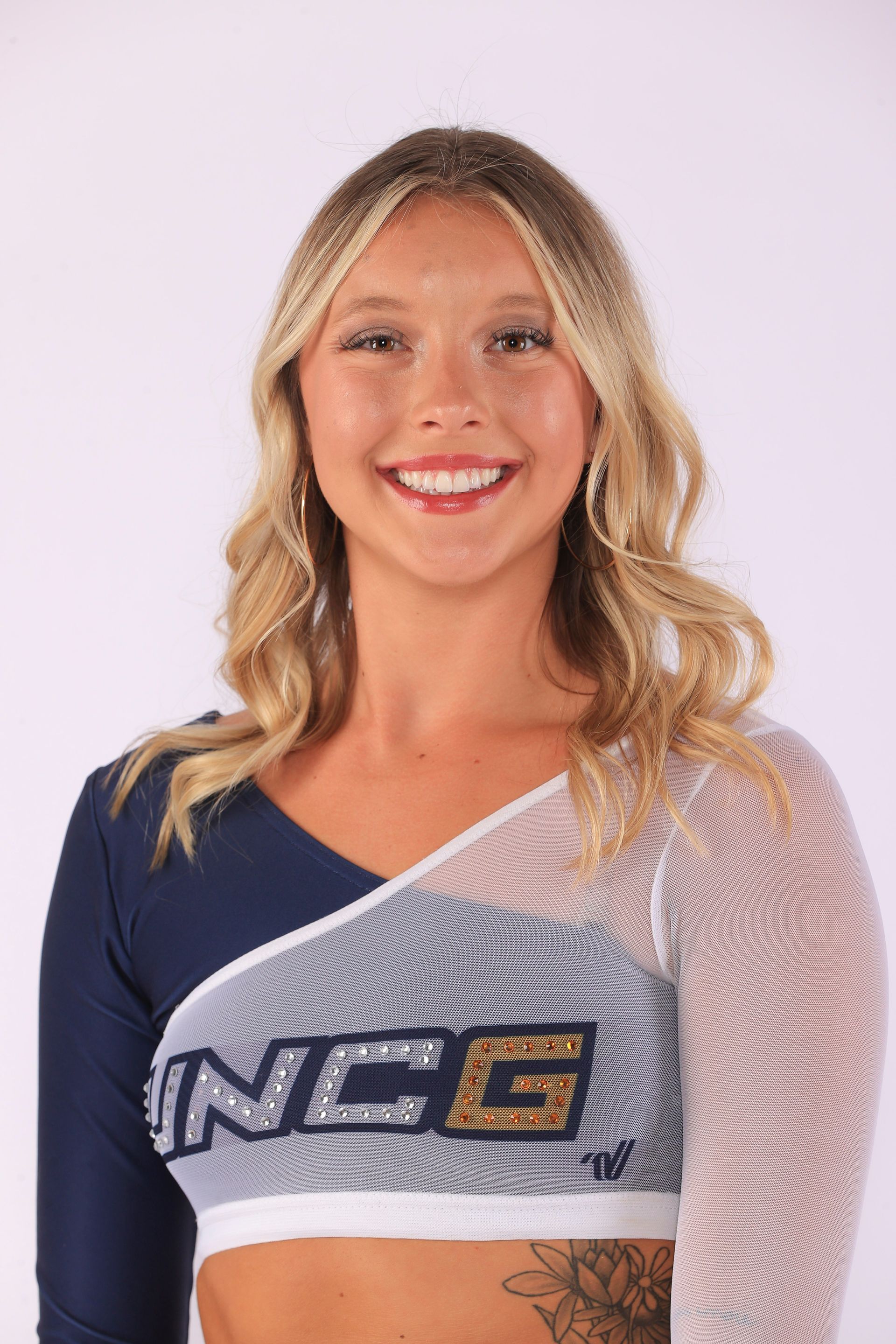 Portrait of a smiling athlete in navy and white NCE uniform on a plain light background