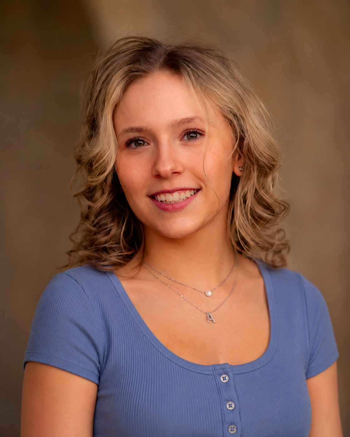 Smiling woman in a blue top against a brown studio backdrop