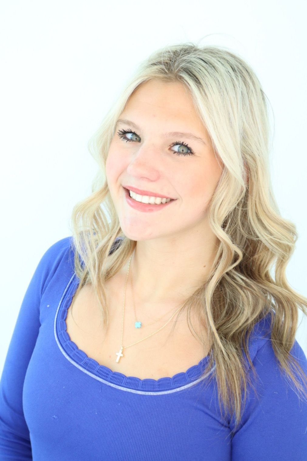 Smiling blonde woman in a blue top against a white background