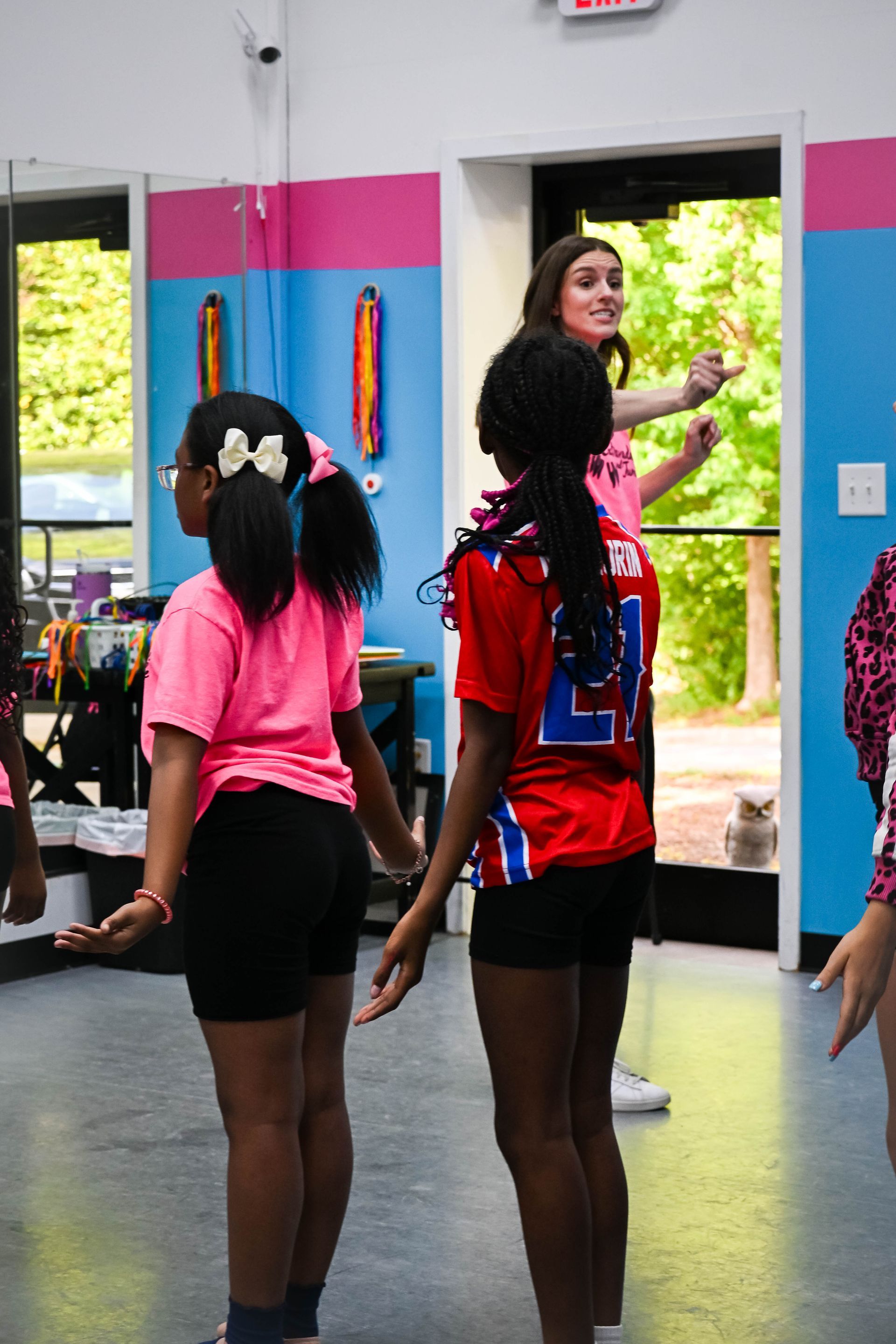 Two dancers in colorful outfits rehearsing in a bright studio near an open door