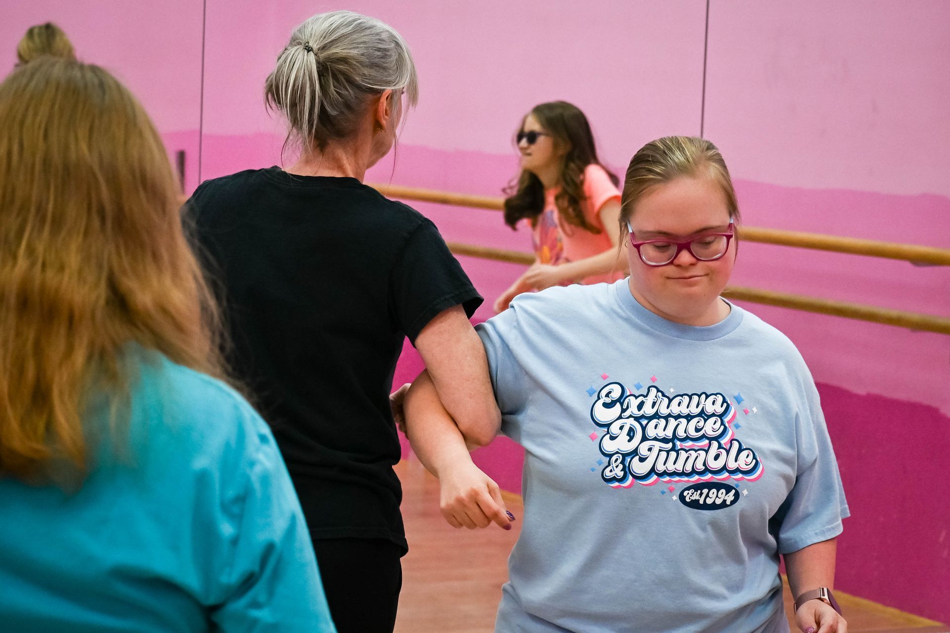 People stretching in a dance studio with pink walls and mirrors