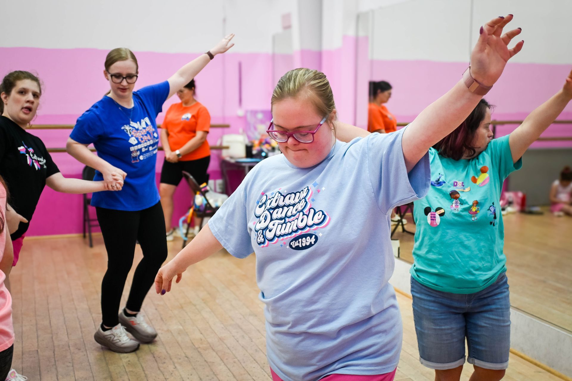 People exercising in a bright studio, raising their arms during a group dance workout