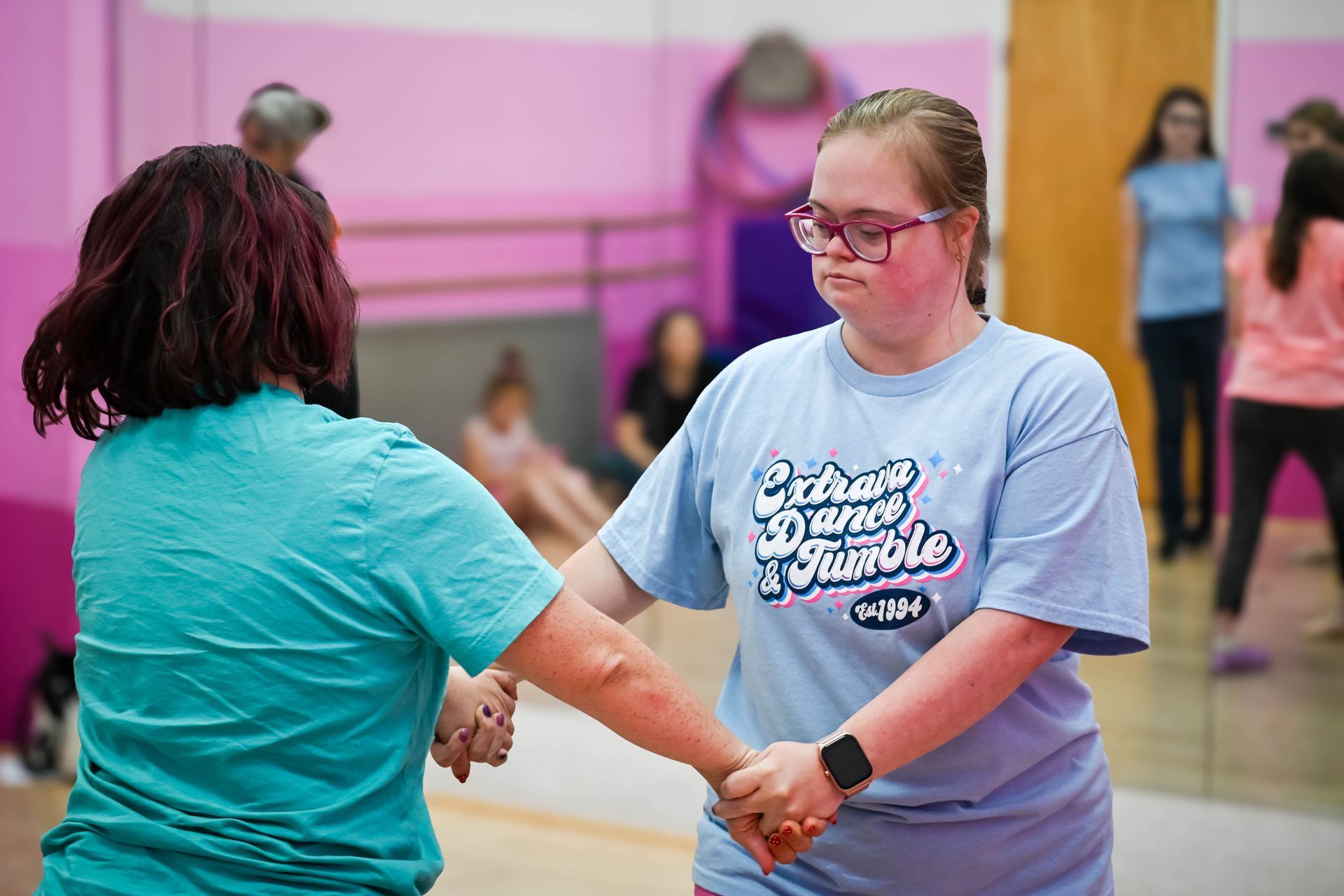 Two people holding hands during a dance or exercise class in a mirrored studio