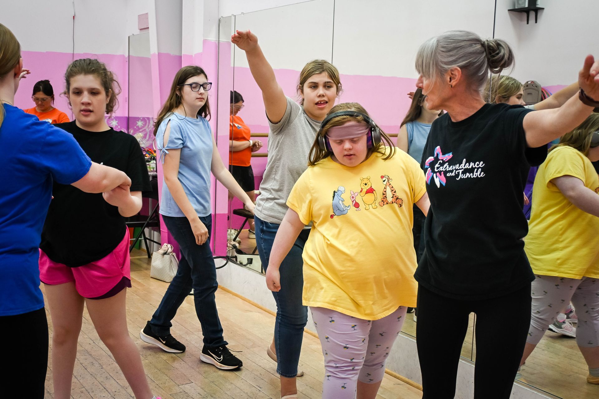 People dancing together in a bright studio, arms raised during a group movement class