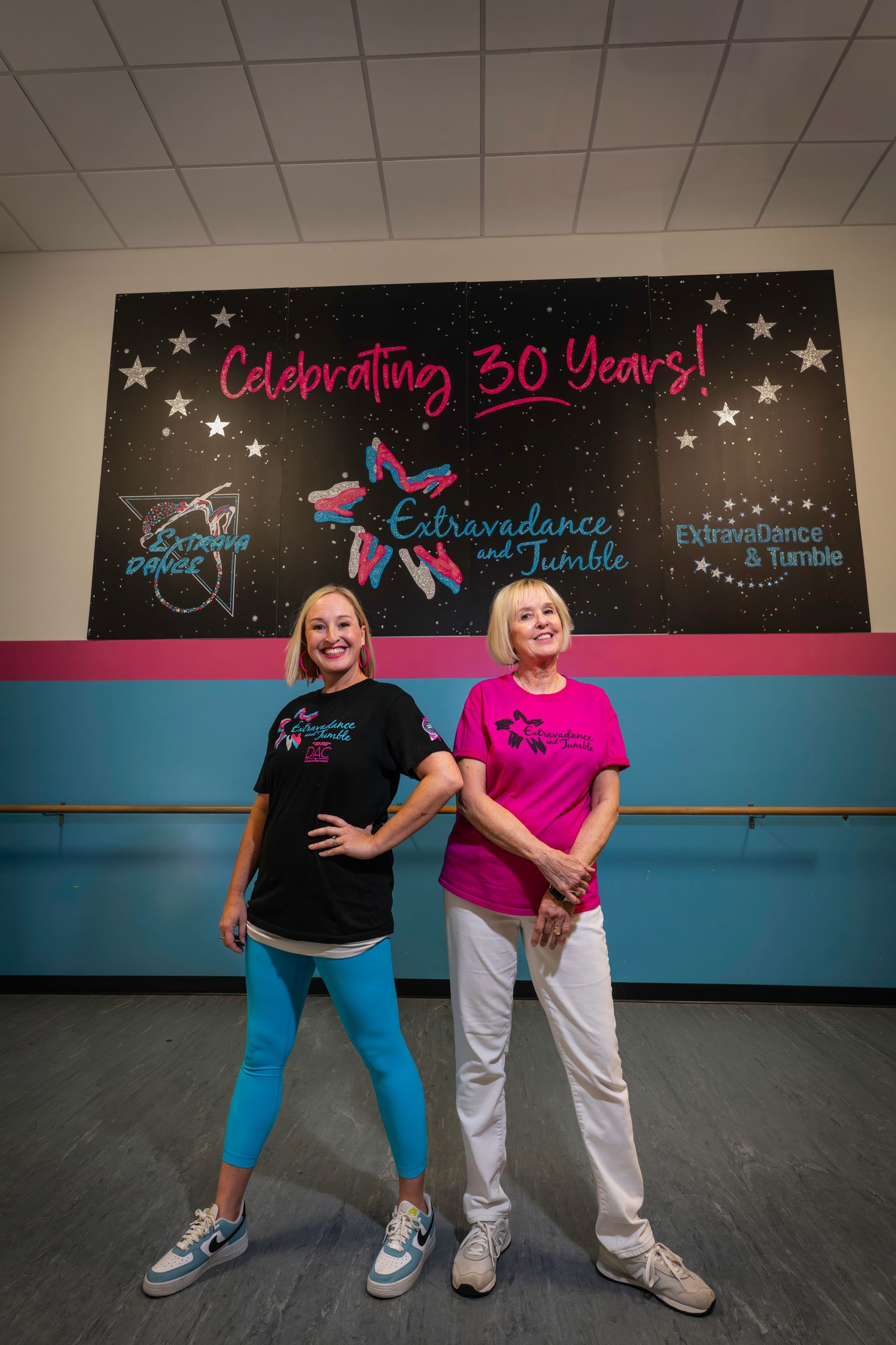 Two dancers posing in front of a “Celebrating 30 Years!” dance studio sign.