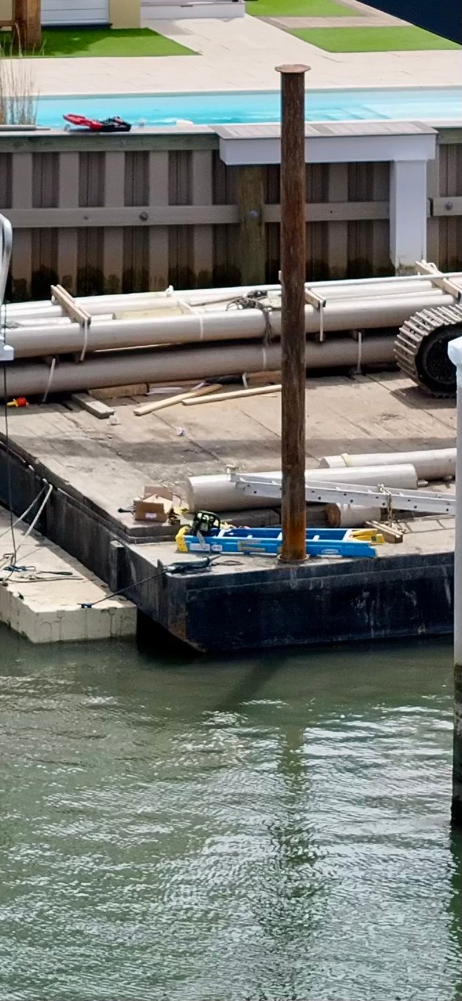 A dock with pipes stacked on top of it in the water.