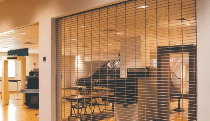 A room with tables and chairs behind a metal grille.