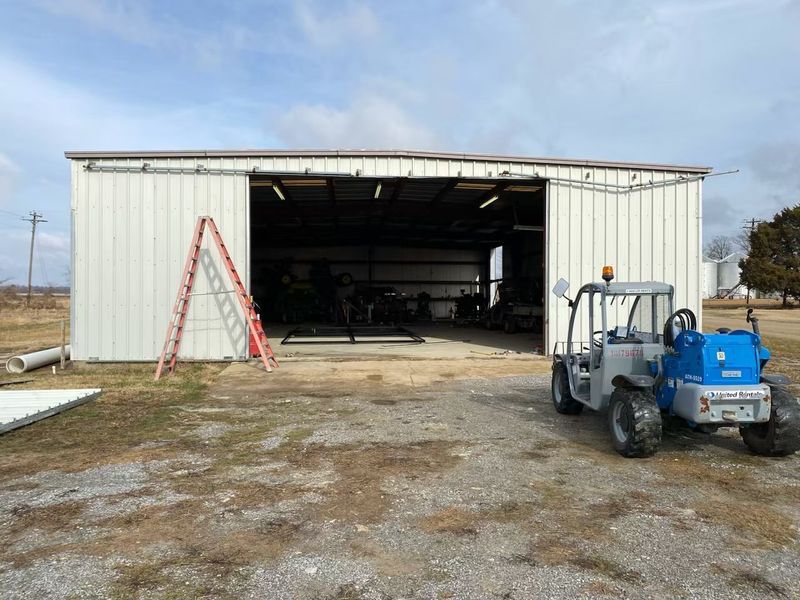 A blue and white tractor is parked in front of a white building.