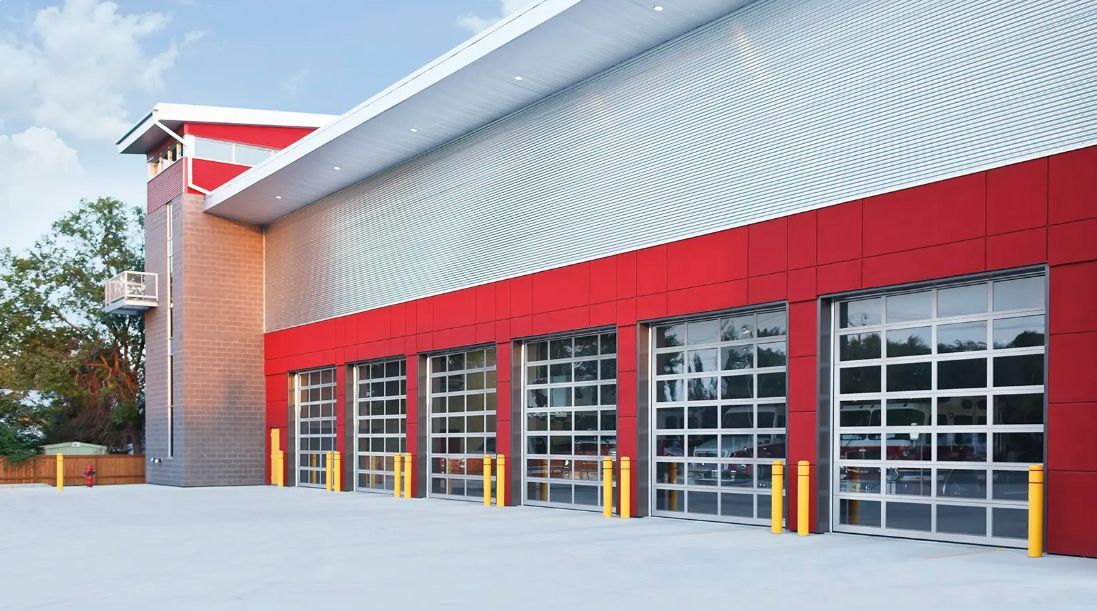 Modern fire station exterior with red accents and glass garage doors.
