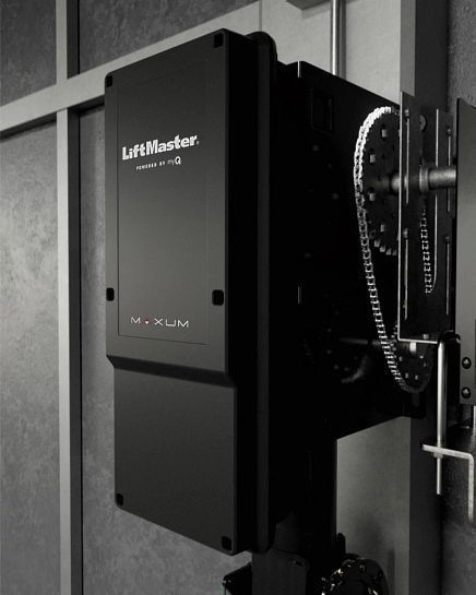 LiftMaster commercial door opener. Black box with chain drive mechanism, mounted indoors.