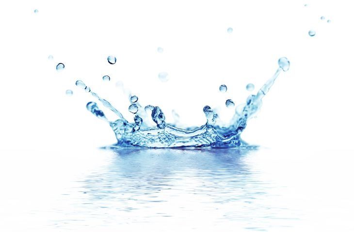 A splash of water forming a crown shape on a white surface, with droplets and reflections.