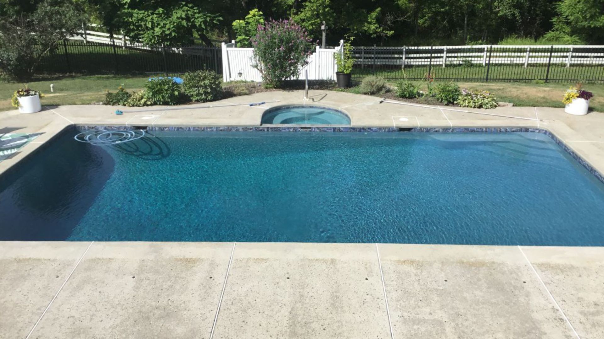 A large swimming pool is sitting on top of a concrete patio.