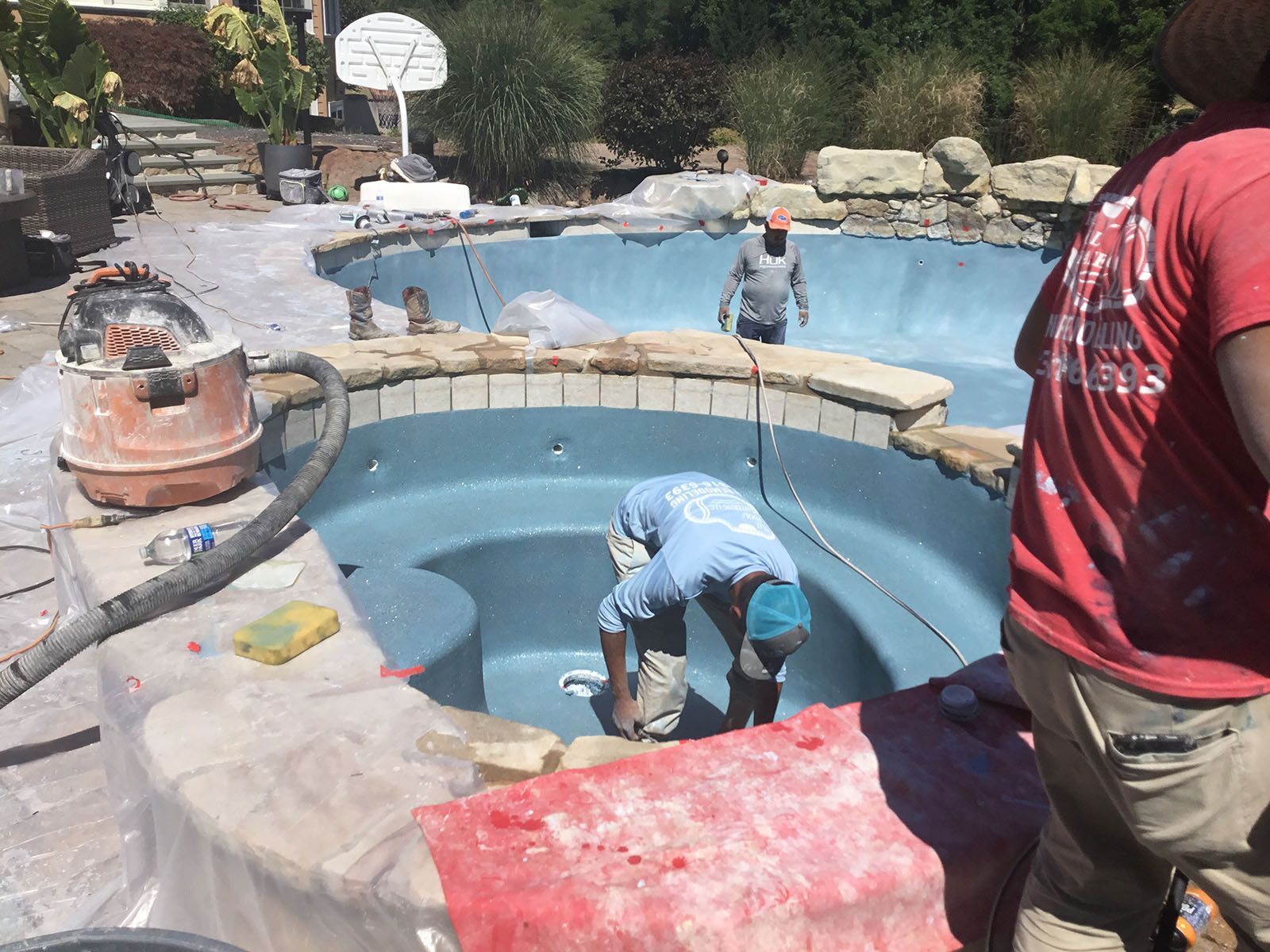 Workers doing a tile and coping repair on big pool
