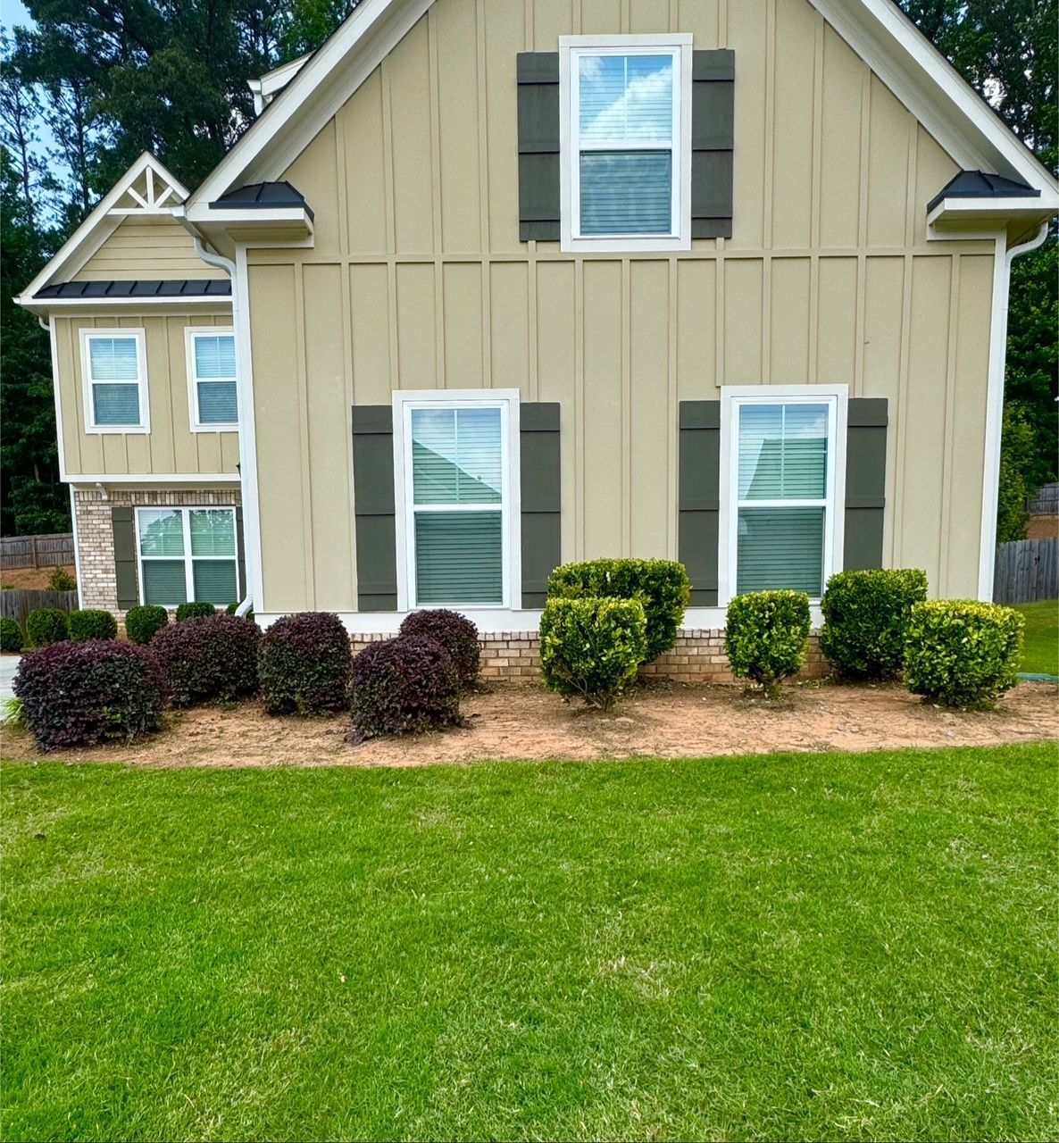 House exterior with green lawn, shrubs, and shutters.