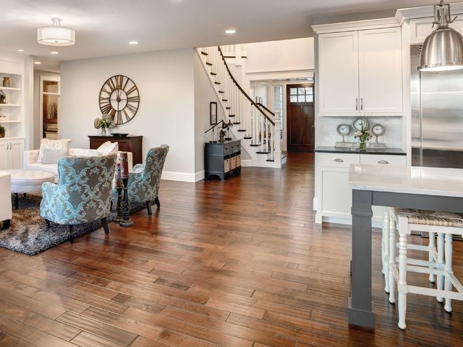 Open-concept living and dining room with hardwood floors, staircase, and white kitchen cabinets