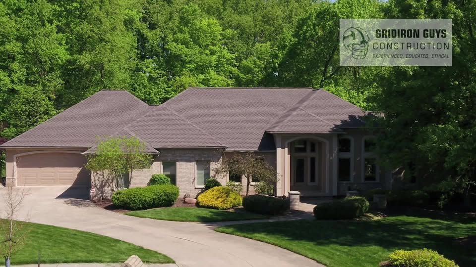 Single-story brick house with a two-car garage, curved driveway, and green trees in front.