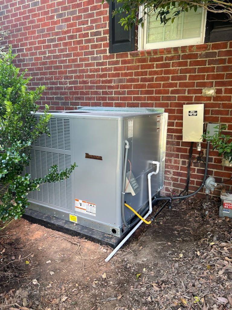 Outdoor HVAC unit beside a brick house with electrical box and conduit