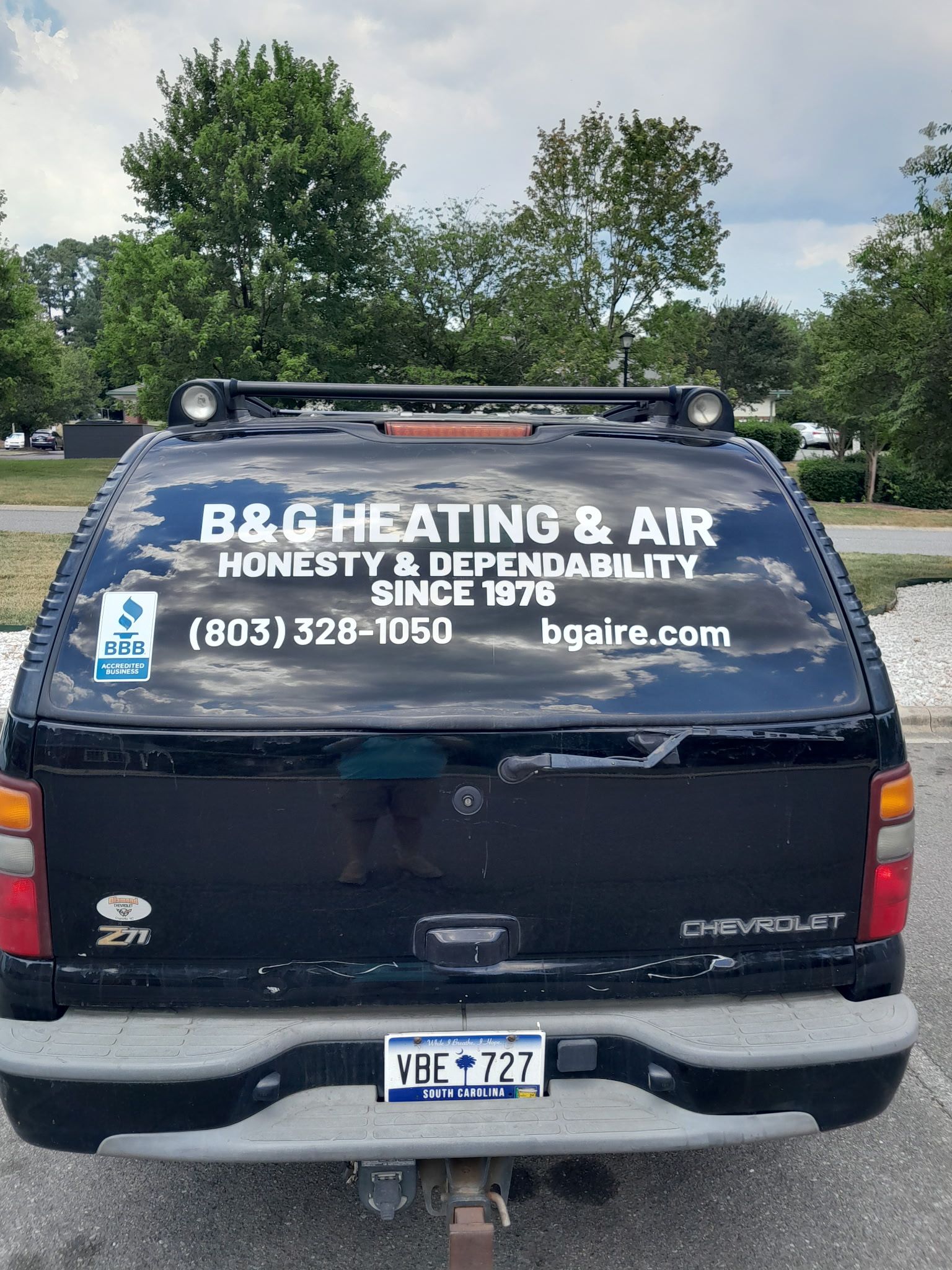 B.G. Heating & Air service van parked outdoors, rear view with company logo and contact info.