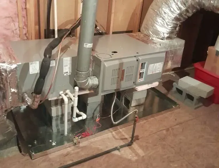 HVAC furnace and ductwork installed on a black platform in a basement utility room