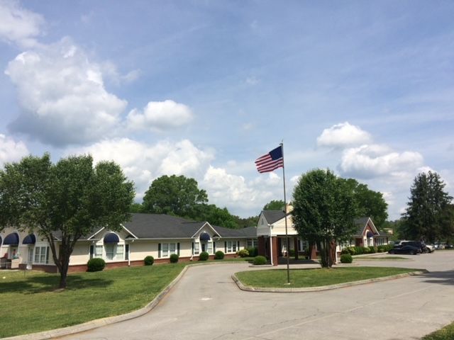 Building with American flag, blue awnings, trees, and cloudy sky.