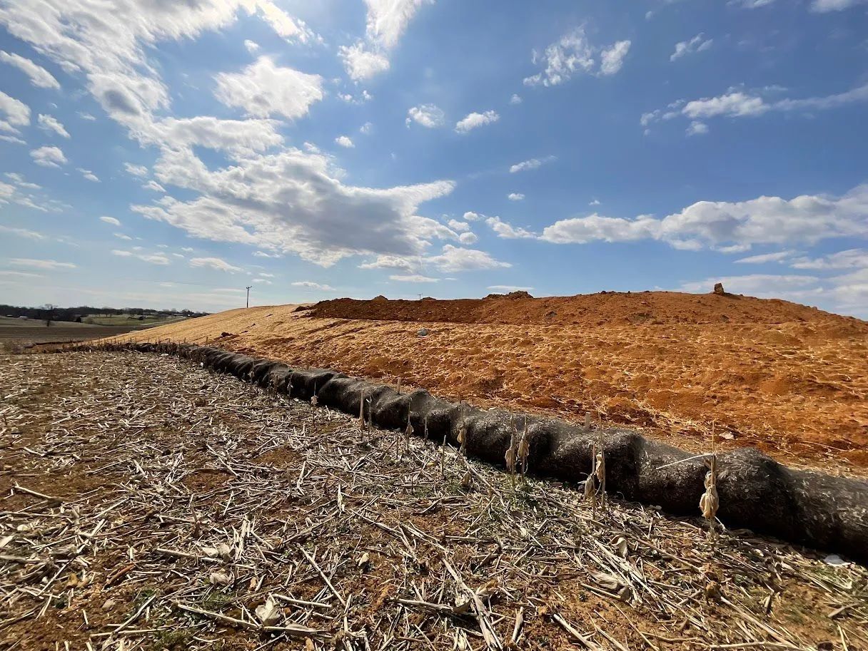 Harvested field with straw bales under a blue, partly cloudy sky
