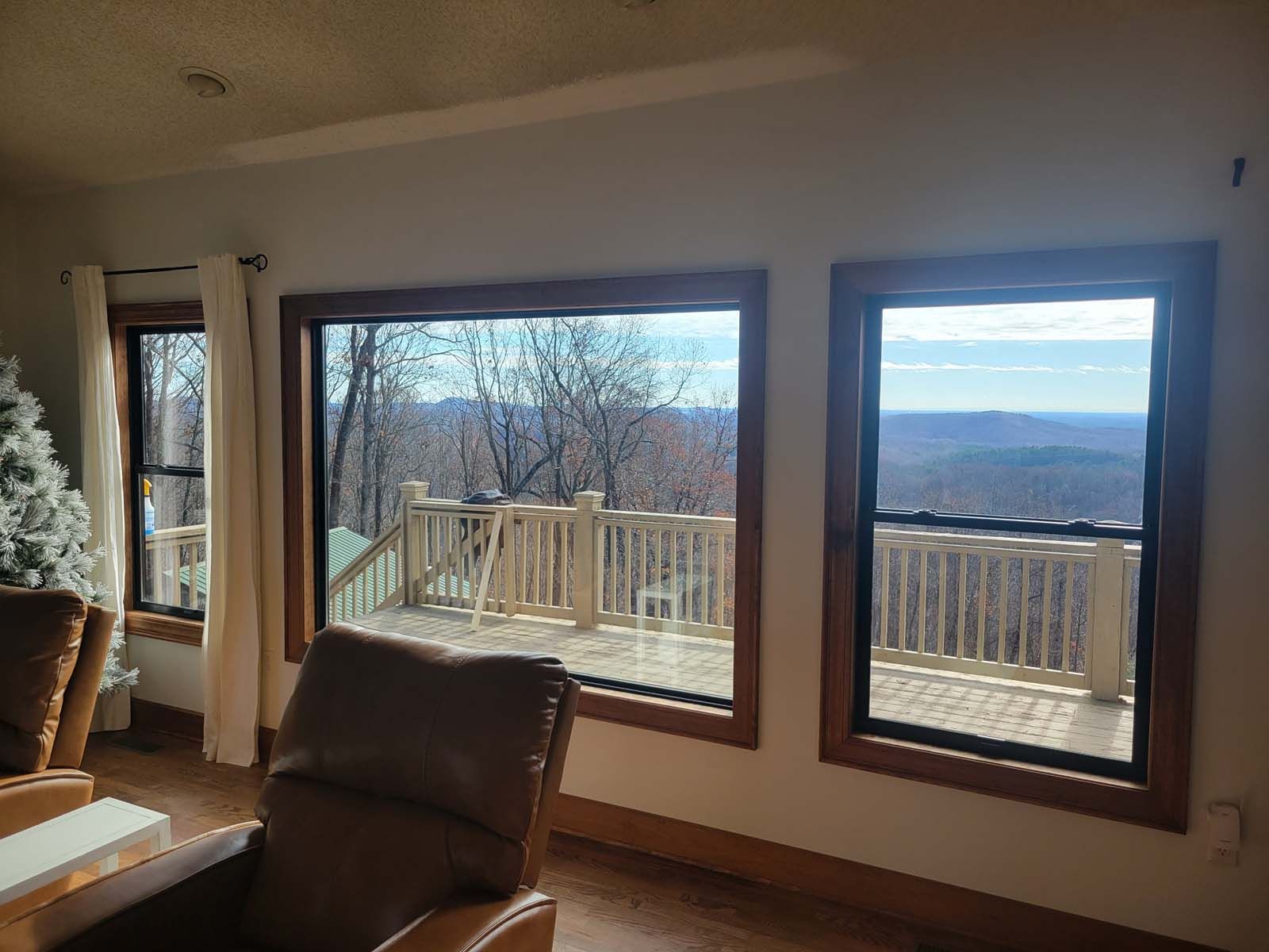 A living room with two large windows and a view of a deck.