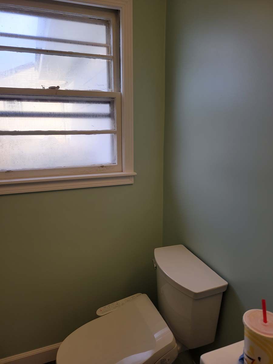 A toilet in a bathroom next to a window