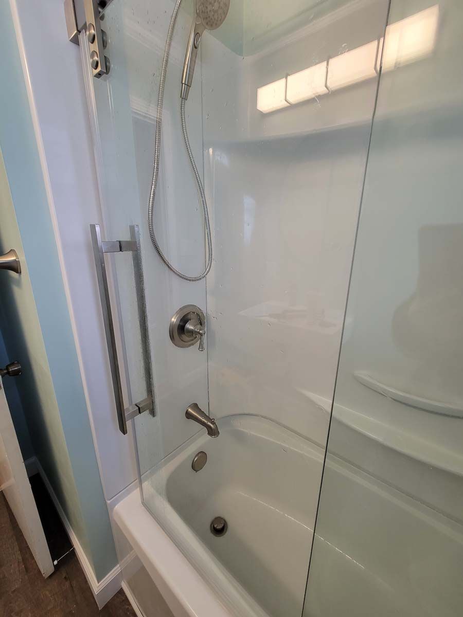 A bathroom with a bathtub and a shower with a glass door.