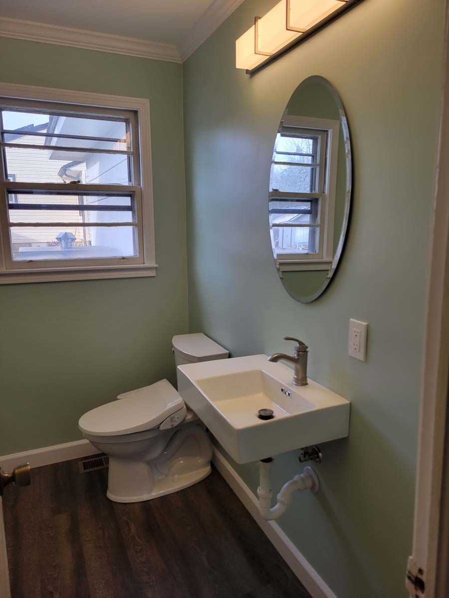 A bathroom with a toilet , sink and mirror.