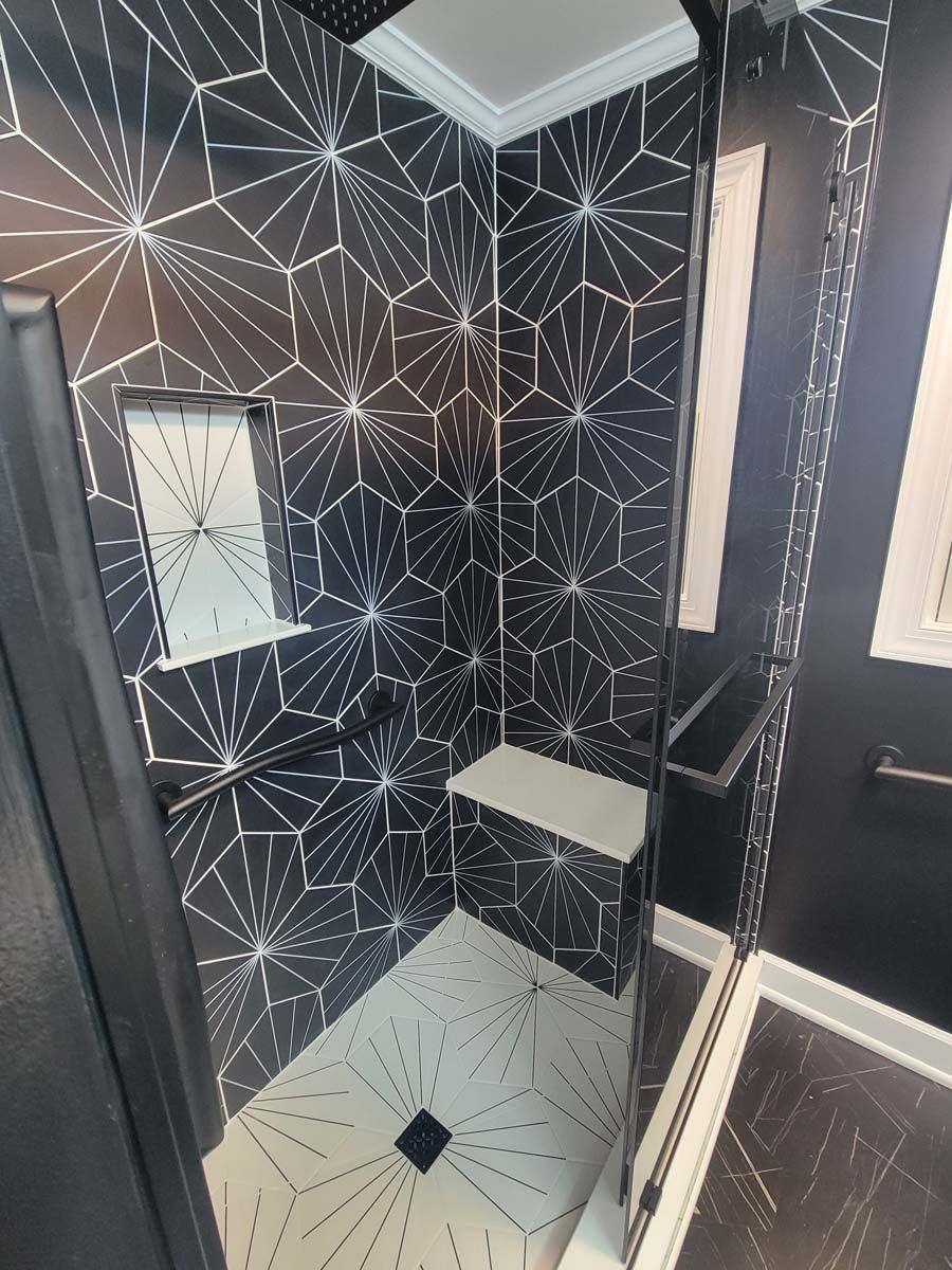 A bathroom with black and white tiles and a walk in shower.