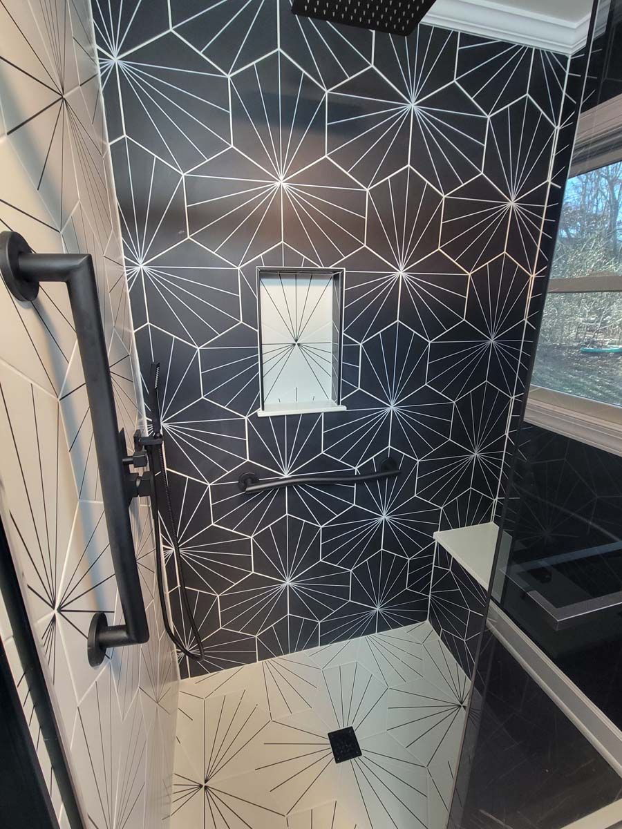 A bathroom with black and white tiles and a shower head.