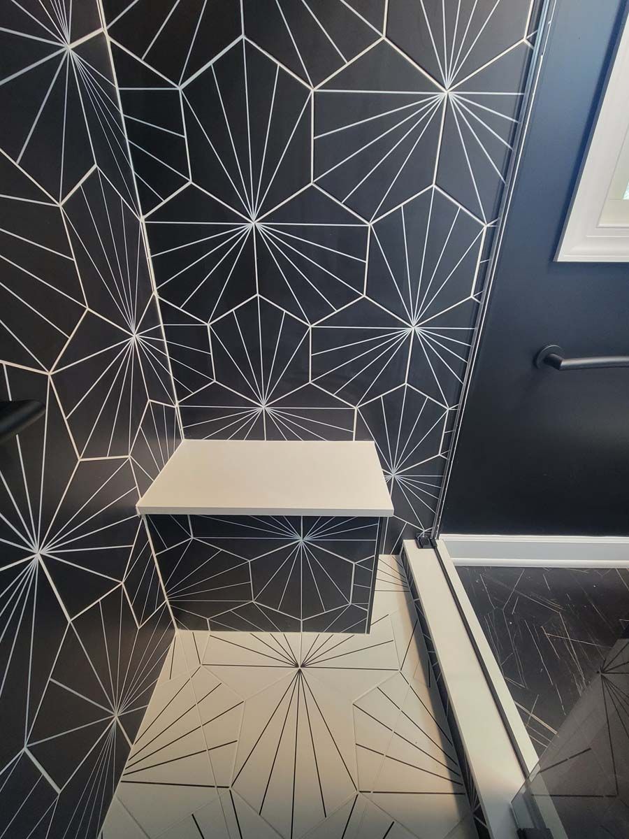 A bathroom with black tiles and a white bench