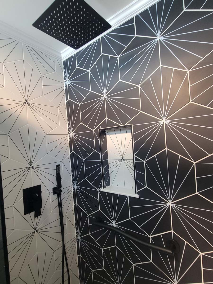 A bathroom with black and white tiles and a black shower head.