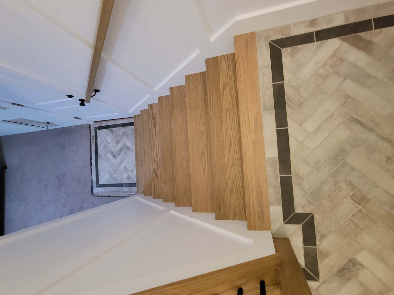 A wooden staircase with a herringbone pattern on the floor