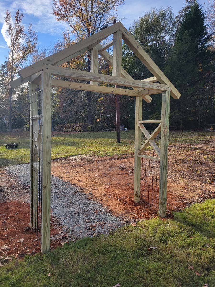 A wooden structure is being built in the middle of a grassy field.