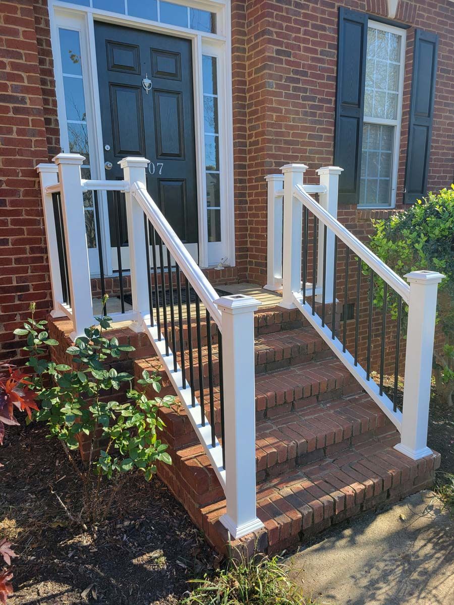 A brick house with a white railing and stairs leading up to the front door.
