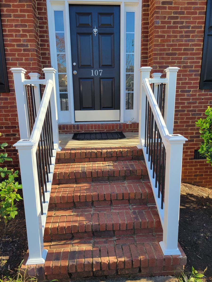 A brick house with stairs leading up to the front door and a white railing.