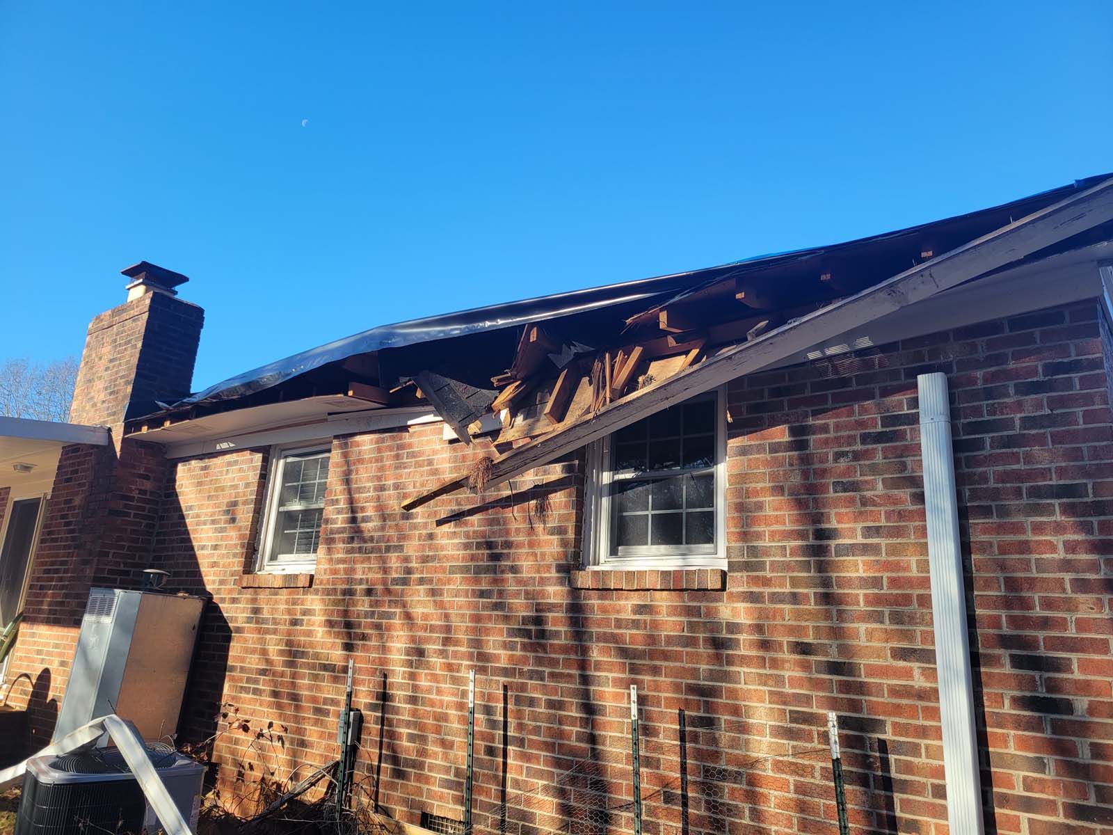 A brick house with a roof that has been damaged by a fire.