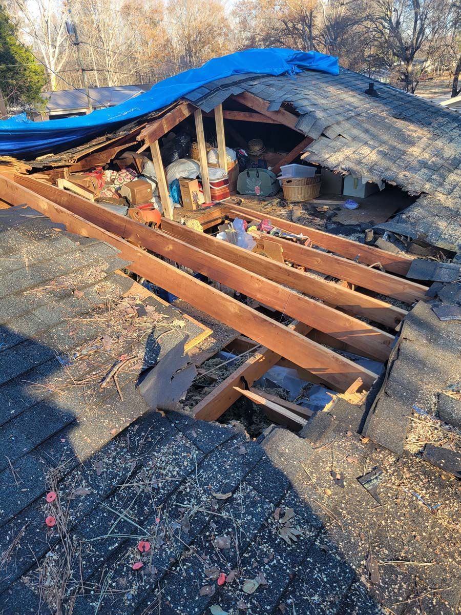 A roof with a hole in it and a blue tarp on top of it.
