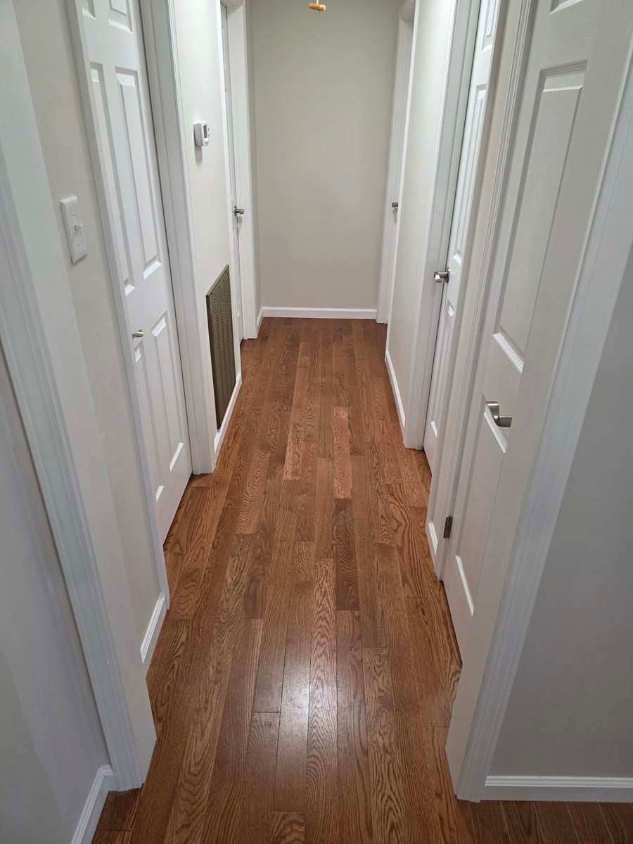 A hallway with hardwood floors and white doors in a house.