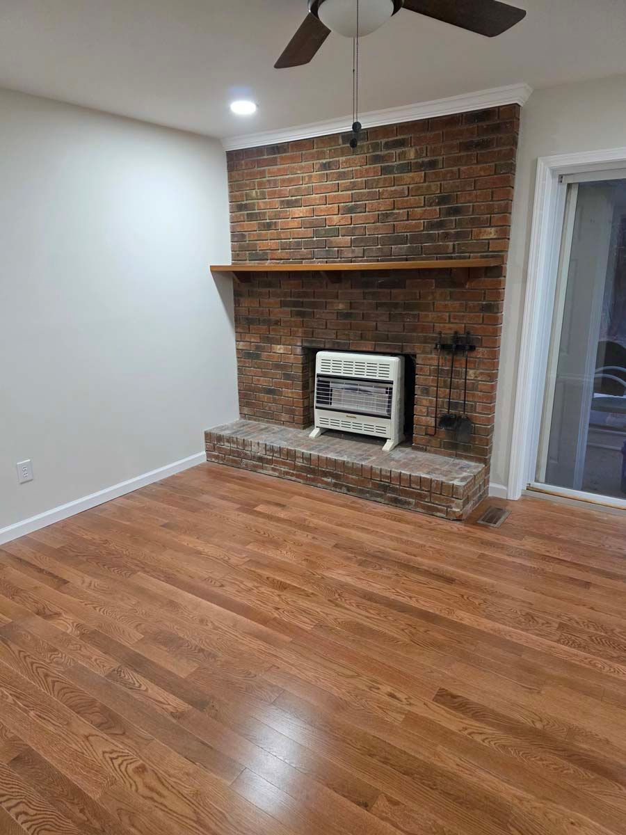 A living room with a fireplace and a ceiling fan.