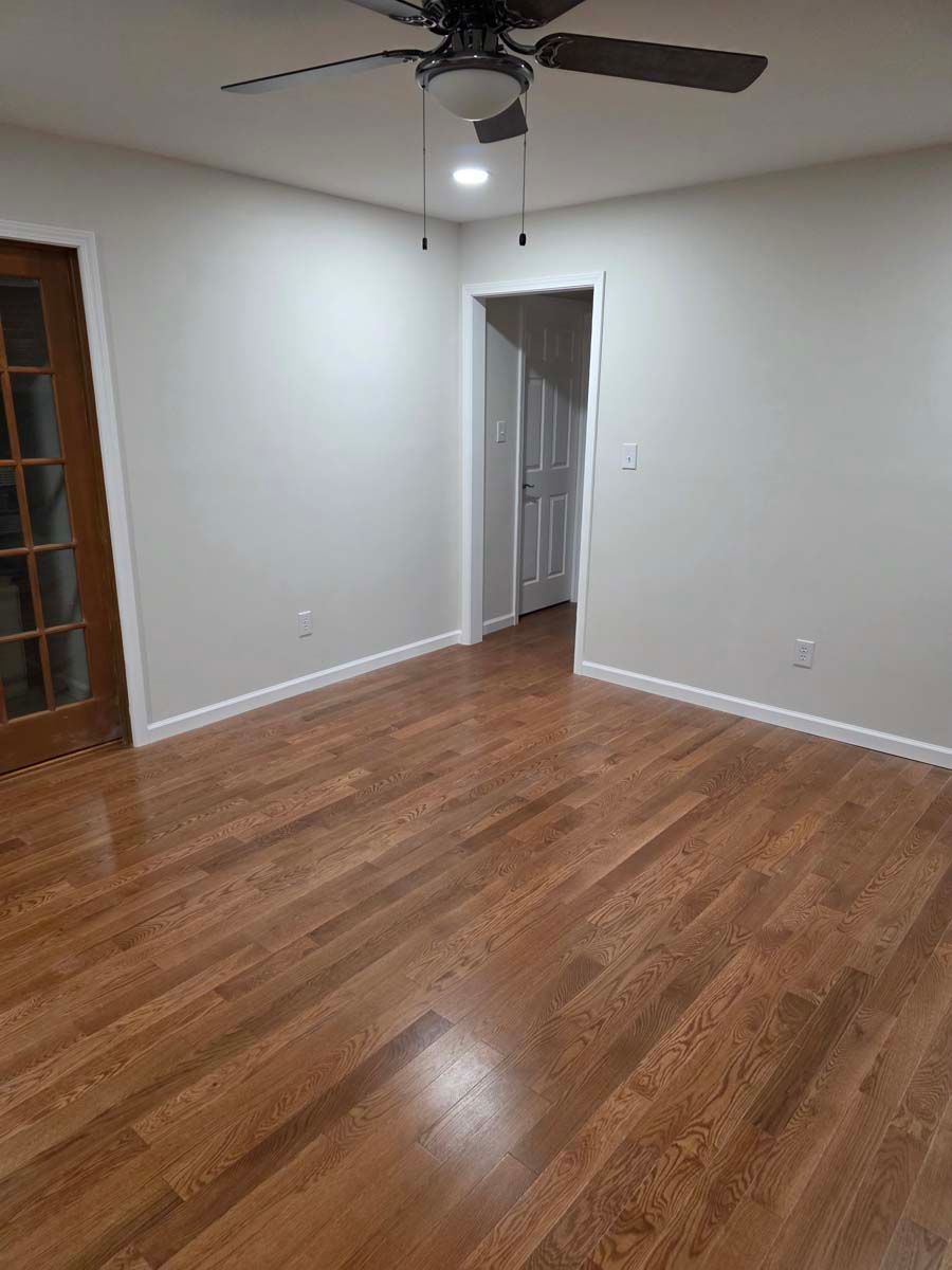 A living room with hardwood floors and a ceiling fan.