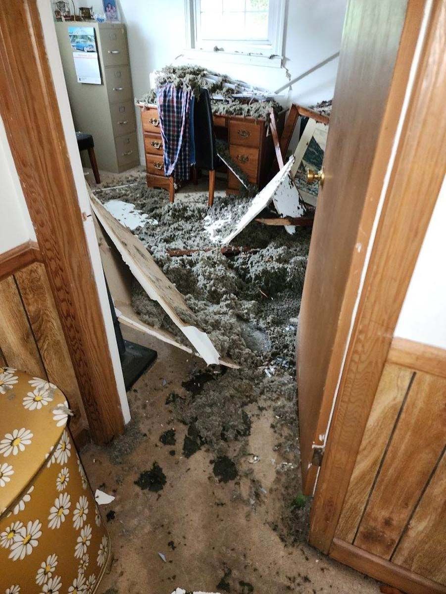 A room with a lot of trash on the floor and a desk.