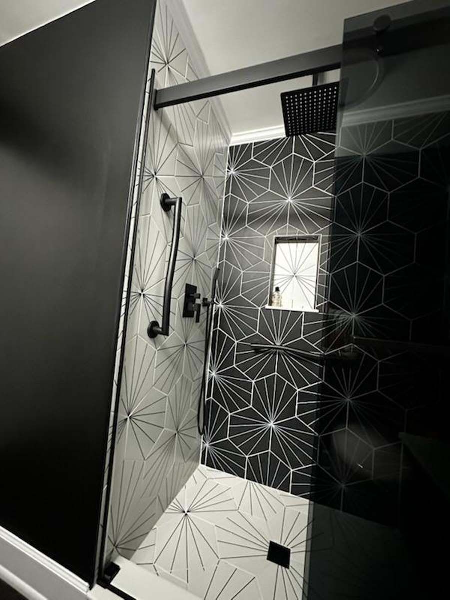 A bathroom with black and white tiles and a walk in shower.