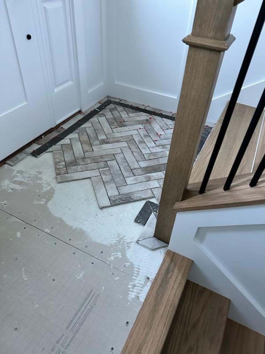 A staircase with a herringbone pattern on the floor and a wooden railing.