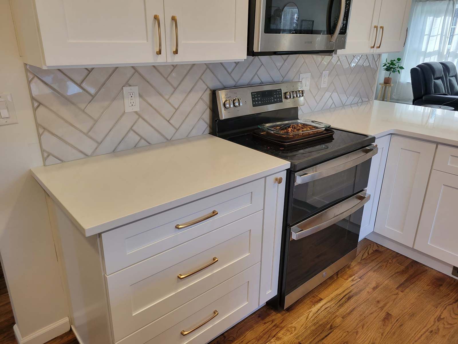 A kitchen with a stove , oven , microwave and white cabinets.