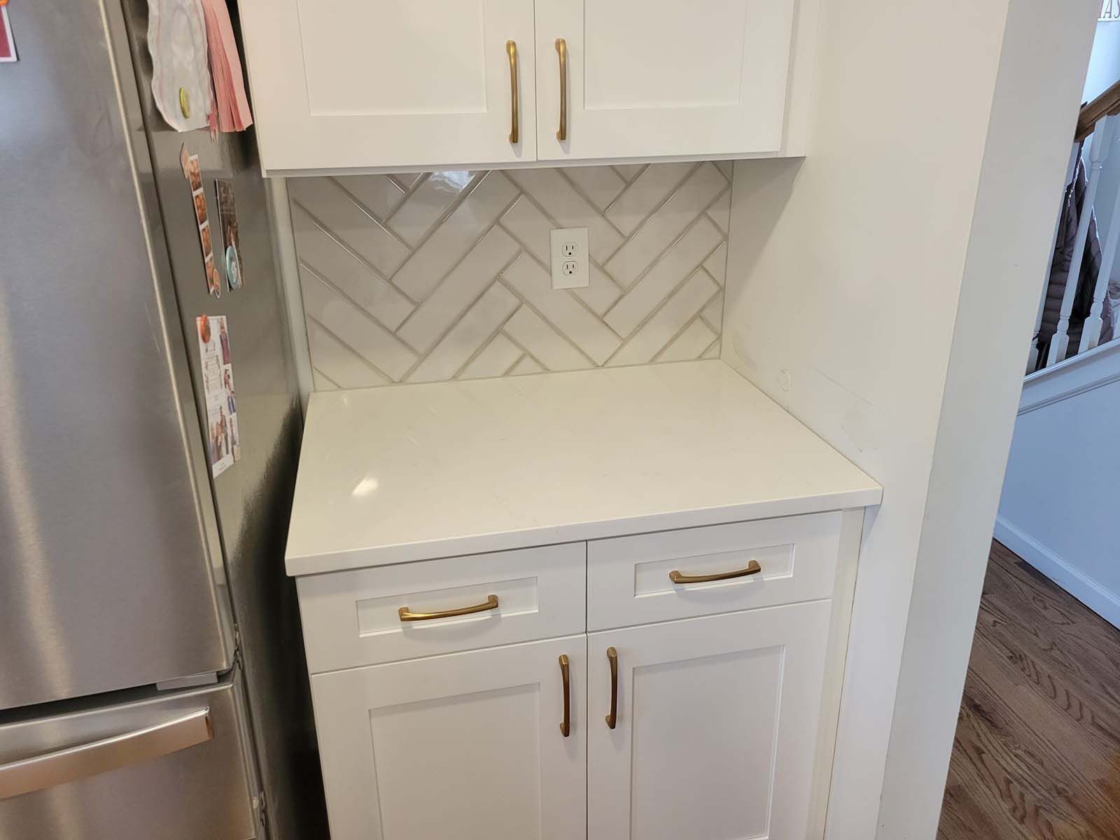 A kitchen with white cabinets and a stainless steel refrigerator.